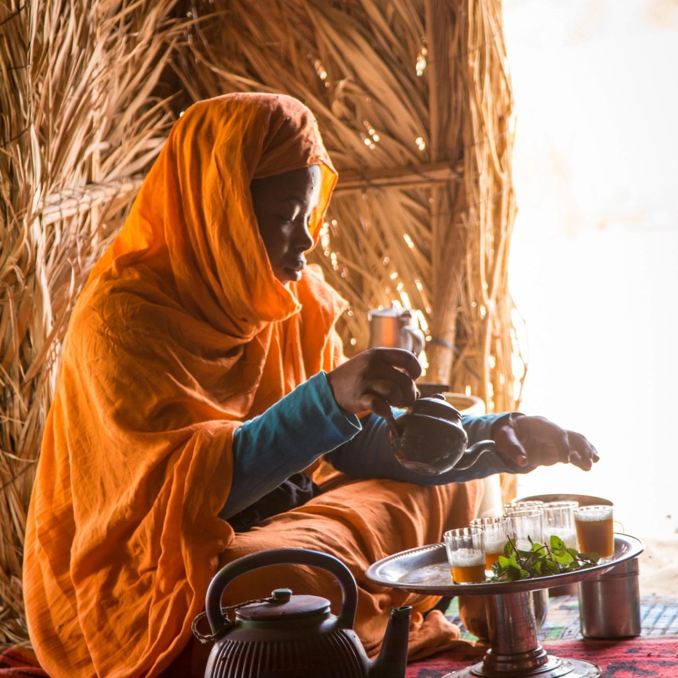 A Mauritanian woman serves traditional tea inside her home, offering a warm glimpse into the rich hospitality and cultural traditions of daily life in the Sahara. Surrounded by beautifully woven textiles, soft desert light, and handcrafted details, the intimate scene reflects the importance of tea ceremonies as a symbol of welcome, connection, and community in Mauritanian culture. Her traditional attire and graceful movements capture the timeless rhythm of life in this remote and fascinating corner of North Africa, where ancient customs remain deeply rooted in everyday life.
Inspiration Africa specializes in bespoke, tailor-made journeys across Mauritania and the African continent, creating immersive travel experiences that connect travelers with authentic cultural encounters, extraordinary desert landscapes, and meaningful human connections. From exploring the vast dunes of the Sahara to experiencing traditional Mauritanian hospitality, every itinerary is carefully curated to showcase the beauty, diversity, and spirit of Africa.
