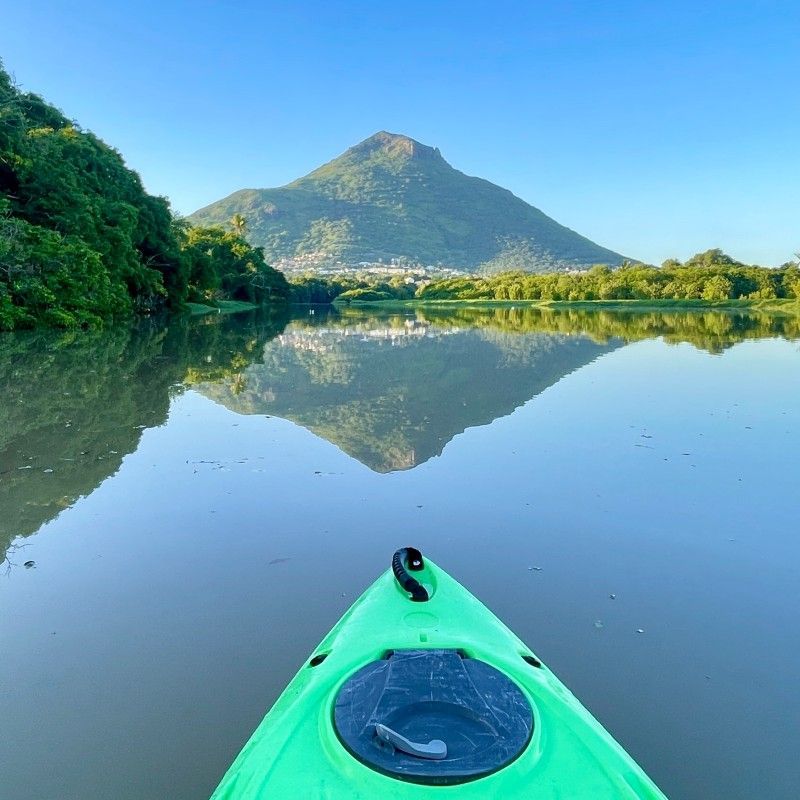 A traveler glides through the calm, emerald waters of the Tamarin River in Mauritius on a kayak, captured in this serene adventure travel photograph. Surrounded by lush tropical vegetation and dramatic mountain backdrops, kayaking in the Tamarin River offers an intimate way to explore Mauritius’s hidden natural beauty. Paddlers can encounter vibrant birdlife, mangroves, and tranquil waterways, making it an ideal experience for nature lovers and adventure seekers alike. This peaceful river journey highlights the island’s diverse landscapes beyond its famous beaches. Inspiration Africa creates bespoke, tailor-made trips to Mauritius and across Africa, combining authentic adventure, immersive nature experiences, and unforgettable destinations for travelers seeking unique and personalized journeys.