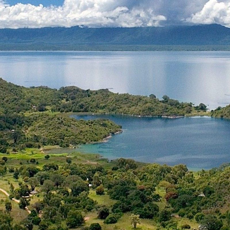 An aerial view of Likoma Island set within the clear blue waters of Lake Malawi is captured in this striking travel photograph, highlighting the island’s remote beauty and tranquil setting. From above, the shoreline curves gently around sandy beaches and rocky outcrops, while clusters of trees and village structures reveal the island’s quiet, lived-in character. The surrounding lake stretches toward the horizon, emphasizing the sense of isolation and escape that defines Likoma Island. Soft natural light enhances the contrast between land and water, creating a calm, expansive atmosphere. This image reflects the allure of Lake Malawi as a destination for relaxation, culture, and exploration. Inspiration Africa designs bespoke, tailor-made journeys to Malawi and across Africa, combining island escapes with immersive travel experiences in remarkable destinations.