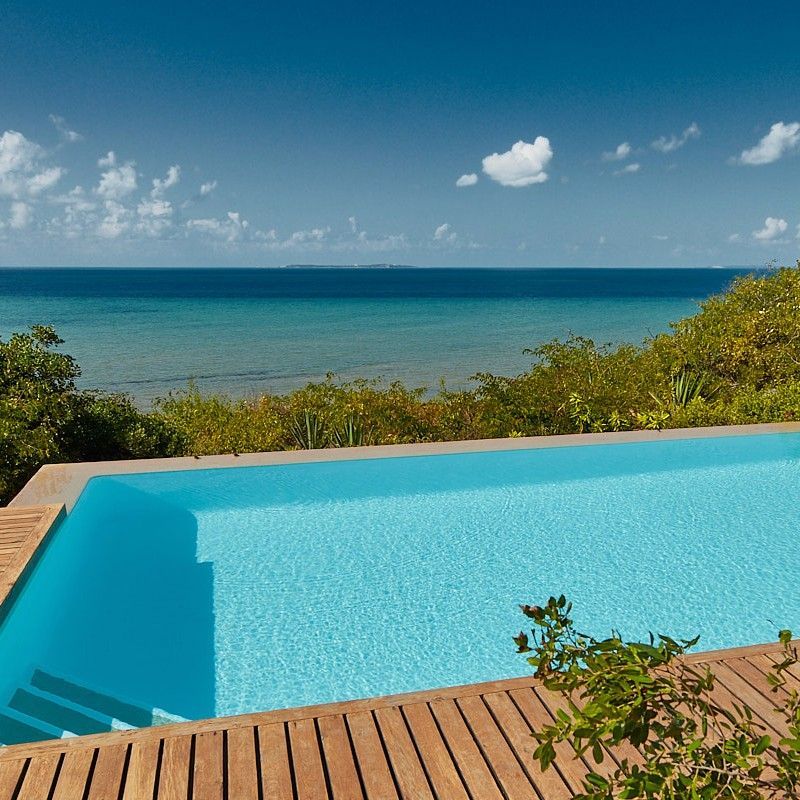 The swimming pool at AsDunas Lodge in Mozambique is beautifully captured in this tranquil travel photograph, overlooking the vast expanse of the Indian Ocean. Set atop coastal dunes, the pool offers elevated views across golden sands and rolling waves, creating a seamless connection between water, sky, and sea. Natural tones, simple elegant design, and surrounding vegetation reflect the lodge’s understated, eco-conscious style, while sun loungers invite moments of quiet relaxation. The scene conveys serenity, space, and a deep sense of escape, highlighting AsDunas Lodge as a peaceful coastal retreat where the rhythm of the ocean shapes every moment. Inspiration Africa specializes in bespoke, tailor-made journeys to Mozambique and across Africa, crafting unforgettable travel experiences in extraordinary destinations.
