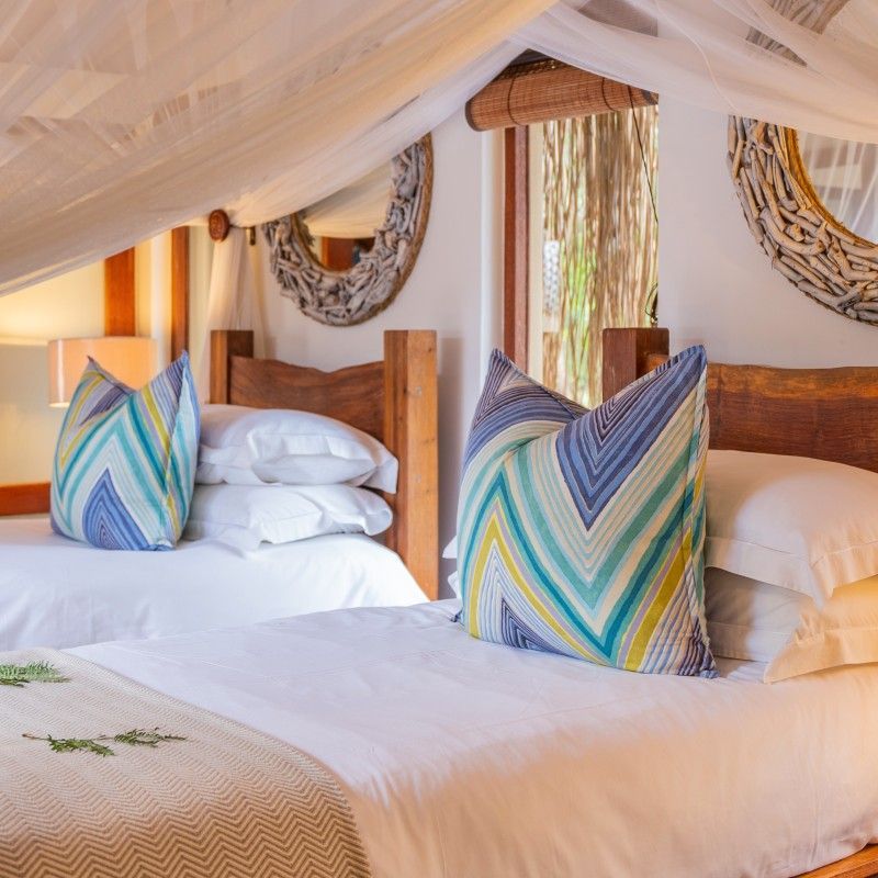 One of the bedrooms in a villa at Azura Benguerra in the Bazaruto Archipelago, Mozambique, is captured in this elegant travel photograph, showcasing a light-filled, coastal-inspired space designed for comfort and relaxation. The room features a luxurious bed with crisp linens, natural wooden furnishings, and soft neutral tones that complement the tropical surroundings. Large windows or sliding doors open onto private decks, offering unobstructed views of the turquoise ocean and lush island vegetation. Thoughtful décor and spacious design create a serene and intimate atmosphere, conveying understated luxury and a seamless connection to the natural environment. The scene highlights Azura Benguerra as a premier island retreat, where comfort, privacy, and stunning coastal vistas combine for an unforgettable experience. Inspiration Africa specializes in bespoke, tailor-made journeys to Mozambique and across Africa, crafting unforgettable travel experiences in extraordinary destinations.
