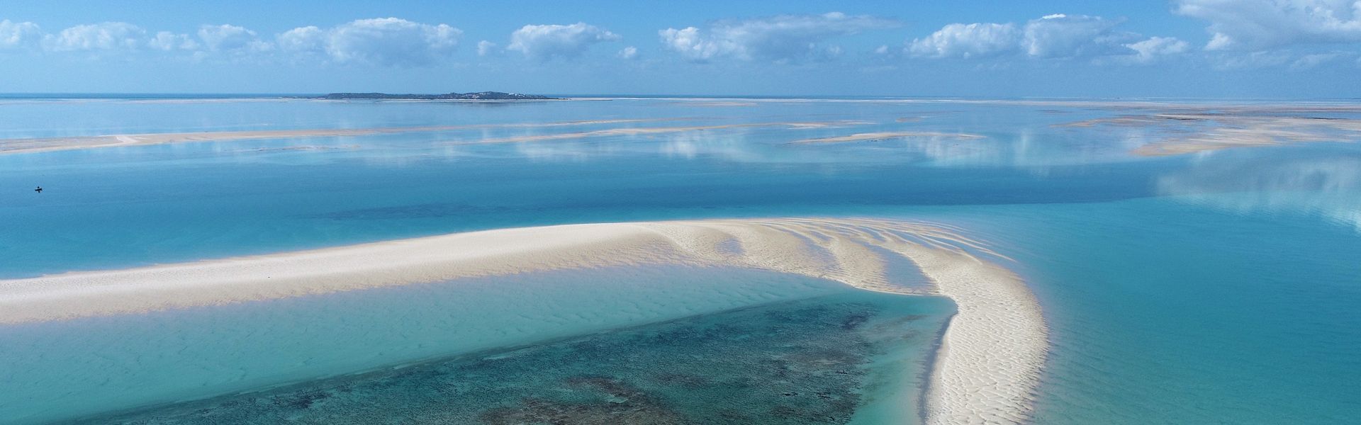 An aerial view captures the stunning turquoise waters and pristine sandbanks of the Bazaruto Archipelago in Mozambique, creating a breathtaking travel photograph. The shallow, crystal-clear lagoons shimmer in varying shades of blue, while the white sandbanks curve gracefully through the Indian Ocean, highlighting the archipelago’s unspoiled natural beauty. The Bazaruto Archipelago is renowned for its vibrant marine life, coral reefs, and secluded beaches, making it one of Africa’s premier coastal destinations. Ideal for photographers, nature lovers, and adventure travelers, this scene captures the serenity, color, and majesty of Mozambique’s idyllic islands and waters. Inspiration Africa specializes in bespoke, tailor-made journeys to Mozambique and across Africa, crafting unforgettable coastal escapes and extraordinary marine experiences.