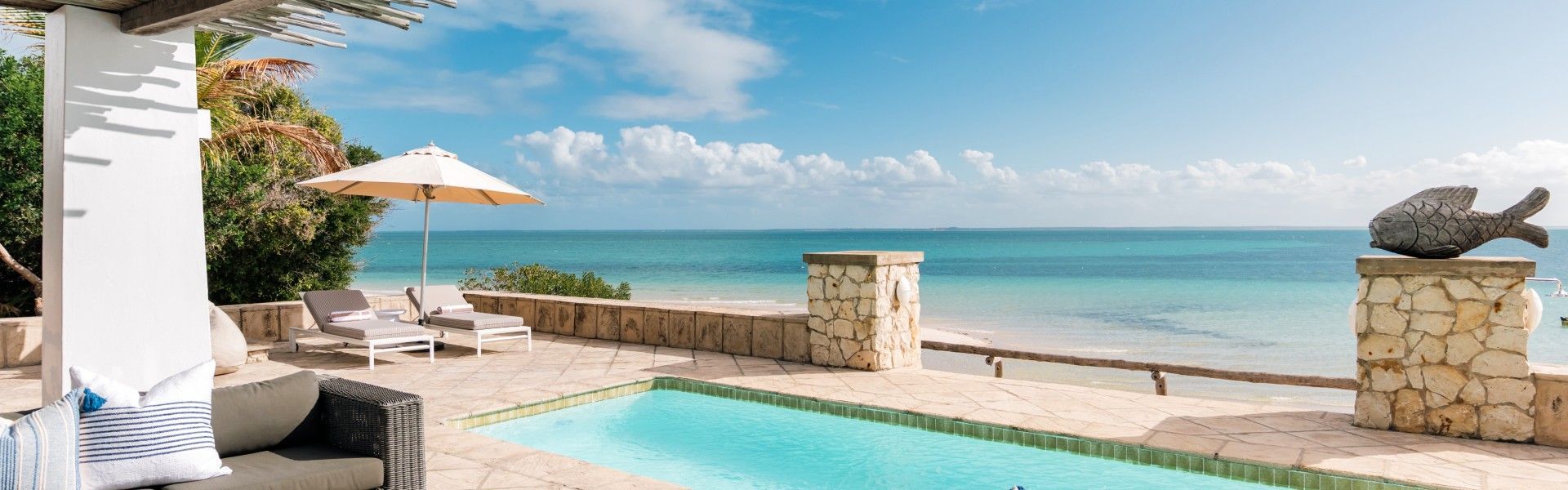 The pool at Azura Marlin Beach in the Bazaruto Archipelago, Mozambique, is captured in this idyllic travel photograph, overlooking the endless blue of the Indian Ocean. Set just steps from the shoreline, the pool appears to blend seamlessly with the sea beyond, framed by soft white sands, swaying palms, and open skies. Sun loungers and shaded areas invite relaxed moments of leisure, while the gentle contrast between the turquoise pool and the deeper ocean hues enhances the sense of barefoot luxury. The scene conveys tranquility, exclusivity, and natural beauty, highlighting Azura Marlin Beach as a refined island escape where ocean views and serene surroundings define the experience. Inspiration Africa specializes in bespoke, tailor-made journeys to Mozambique and across Africa, crafting unforgettable travel experiences in extraordinary destinations.
