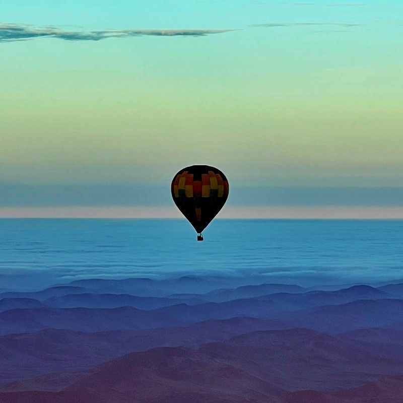 Gaze upon a breathtaking balloon flight drifting above the iconic dunes of Sossusvlei in Namibia. This striking aerial photograph captures hot air balloons floating over towering red sand dunes and pale clay pans, illuminated by soft morning light. From above, the dramatic patterns and vast scale of the Namib Desert create a truly surreal and timeless landscape. Experiencing Sossusvlei by balloon offers a peaceful and unforgettable perspective on one of Africa’s most extraordinary natural wonders. Inspiration Africa specializes in designing bespoke, tailor-made journeys that showcase Africa’s most remarkable landscapes and once-in-a-lifetime experiences.