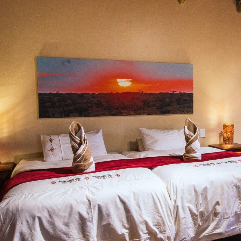 One of the elegantly designed bedrooms at Camelthorn Kalahari Lodge in Namibia is captured in this inviting travel photograph, showcasing a seamless blend of comfort and African-inspired style. Warm earth tones, natural textures, and thoughtfully curated décor create a serene and luxurious atmosphere, while large windows frame views of the surrounding Kalahari landscape, allowing sunlight to fill the room. The bedroom reflects the lodge’s commitment to providing a refined yet authentic safari experience, combining modern amenities with the wild beauty of Namibia. Ideal for luxury travelers, safari enthusiasts, and those seeking relaxation in the heart of the desert, this scene captures the elegance, tranquility, and immersive connection to nature that defines Camelthorn Kalahari Lodge. Inspiration Africa specializes in bespoke, tailor-made journeys to Namibia and across Africa, crafting unforgettable lodge stays and extraordinary safari experiences.
