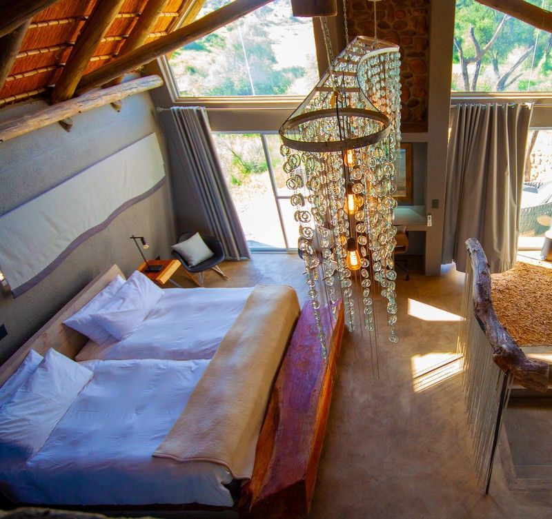 The interior of one of the chalets at Naankuse Lodge in Namibia is showcased in this inviting travel photograph, highlighting a warm and thoughtfully designed space that blends comfort with natural surroundings. A comfortable bed and wooden furnishings create a cozy, relaxing atmosphere, while soft neutral tones and subtle décor reflect the textures and colors of the Namibian landscape. Large windows allow natural light to fill the room and provide unobstructed views of the bush and wildlife nearby, enhancing the sense of immersion in nature. The interior balances authentic safari-style living with understated elegance, offering guests a tranquil retreat within the lodge’s scenic and wildlife-rich environment. Inspiration Africa specializes in bespoke, tailor-made journeys to Namibia and across Africa, crafting unforgettable safari experiences in extraordinary wilderness destinations.