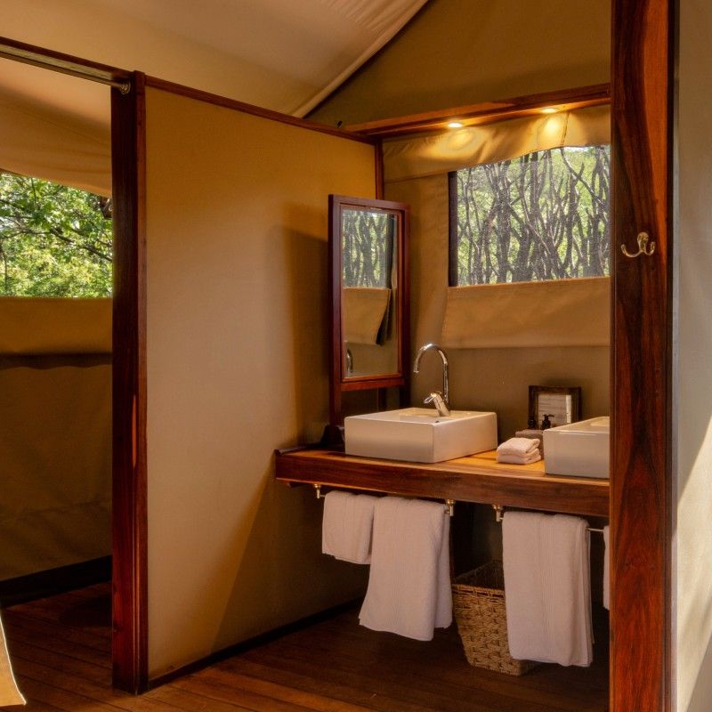 The bathroom at one of the luxurious tents at Ongava Tented Camp in Namibia is captured in this elegant travel photograph, showcasing a seamless blend of comfort, style, and wilderness immersion. Natural materials, warm earthy tones, and thoughtful design details create a serene and inviting space, while large windows and open layouts allow light to flood in and provide views of the surrounding plains. The bathroom reflects the camp’s ethos of combining modern amenities with an authentic safari experience, offering guests a private retreat in the heart of Namibia’s wild landscapes. Ideal for luxury travelers, safari enthusiasts, and design lovers, this scene captures the tranquility, elegance, and immersive connection to nature that define Ongava Tented Camp. Inspiration Africa specializes in bespoke, tailor-made journeys to Namibia and across Africa, crafting unforgettable safari stays and extraordinary lodge experiences.
