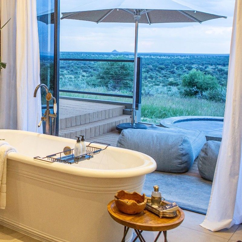 The bathroom at Otijwa Mountain Lodge in Namibia is captured in this elegant travel photograph, showcasing a luxurious and serene space designed to complement the surrounding wilderness. Natural materials, warm earthy tones, and modern fixtures create a sense of comfort and sophistication, while large windows or open layouts allow light to flood the space and offer sweeping views of the surrounding savannah and distant hills. The design balances contemporary luxury with a deep connection to nature, providing guests with a private and tranquil retreat. Ideal for luxury travelers, safari enthusiasts, and those seeking relaxation immersed in the African wilderness, this scene captures the elegance, serenity, and immersive experience that define Otijwa Mountain Lodge. Inspiration Africa specializes in bespoke, tailor-made journeys to Namibia and across Africa, crafting unforgettable lodge stays and extraordinary safari experiences.