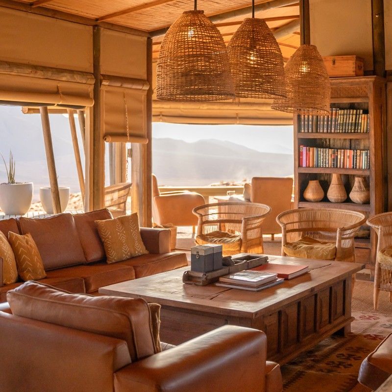 The beautifully decorated interior of the common areas at Wolwedans Desert Lodge in Namibia is captured in this elegant travel photograph, reflecting a refined harmony between luxury and the raw desert environment. Thoughtfully designed spaces feature natural materials, handcrafted furnishings, and warm, earthy tones that echo the surrounding NamibRand landscape. Large open areas and expansive windows invite sweeping desert views inside, creating a seamless connection between indoors and outdoors. The décor embodies Wolwedans’ philosophy of sustainability, authenticity, and understated elegance, offering guests a tranquil place to relax, reflect, and connect. Ideal for luxury travelers, design lovers, and nature enthusiasts, this scene captures the soul, serenity, and timeless beauty of one of Namibia’s most iconic desert lodges. Inspiration Africa specializes in bespoke, tailor-made journeys to Namibia and across Africa, crafting immersive desert lodge experiences and unforgettable moments in extraordinary landscapes.