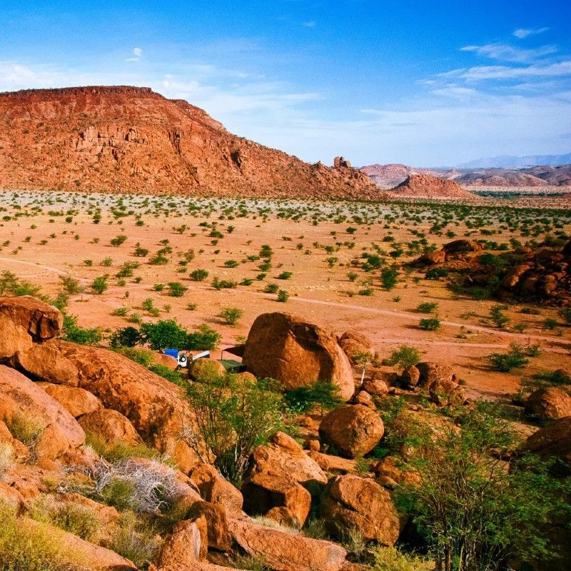 The rugged and dramatic landscape of Damaraland in Namibia is captured in this breathtaking travel photograph, showcasing vast plains, rocky outcrops, and jagged mountains under expansive skies. Sparse vegetation punctuates the arid terrain, while distant ridges and natural formations create a sense of scale, solitude, and timeless beauty unique to this region. Damaraland is renowned for its striking scenery, desert-adapted wildlife, and remote, unspoiled wilderness, offering an extraordinary experience for travelers seeking adventure and connection with nature. Ideal for photographers, safari enthusiasts, and nature lovers, this scene captures the raw grandeur, serenity, and enduring allure of Namibia’s Damaraland. Inspiration Africa specializes in bespoke, tailor-made journeys to Namibia and across Africa, crafting immersive safari experiences and unforgettable encounters with extraordinary landscapes.