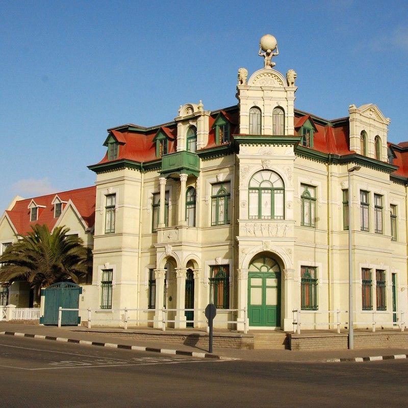 An Art Nouveau building in Swakopmund, Namibia, is captured in this striking travel photograph, showcasing the town’s unique blend of European architectural elegance and coastal charm. Ornate facades, curved lines, decorative motifs, and large windows reflect the distinctive Art Nouveau style, standing out against Swakopmund’s desert-meets-ocean setting. The building’s pastel tones and intricate details highlight the heritage and historical character that give the town its distinctive atmosphere. Ideal for architecture enthusiasts, photographers, and cultural travelers, this scene captures the elegance, creativity, and timeless beauty of Swakopmund’s historic streetscape. Inspiration Africa specializes in bespoke, tailor-made journeys to Namibia and across Africa, crafting immersive cultural experiences and unforgettable encounters with extraordinary heritage sites.