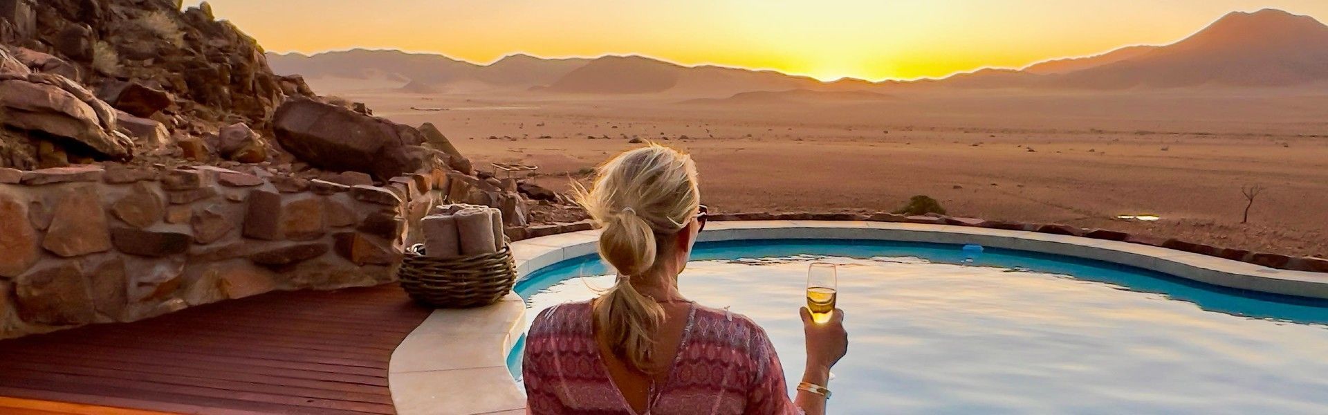 A tranquil sunset unfolds over the vast Namib Desert, viewed from the infinity pool of Namib Outpost in Namibia, captured in this evocative travel photograph. Warm hues of orange, pink, and gold wash across the endless desert plains, while the still water of the pool mirrors the dramatic sky, creating a moment of pure serenity. Perched high above the surrounding landscape, Namib Outpost offers sweeping panoramic views and an unforgettable sense of remoteness and luxury. Ideal for travelers seeking solitude, photographers, and lovers of dramatic desert scenery, this scene captures the magic, scale, and timeless beauty of Namibia at dusk. Inspiration Africa specializes in bespoke, tailor-made journeys to Namibia and across Africa, crafting immersive desert escapes and extraordinary moments in some of the continent’s most breathtaking landscapes.