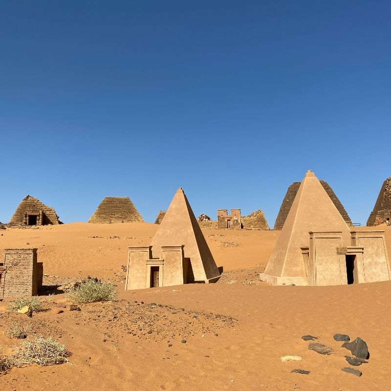 Discover the ancient grandeur of Sudan with this striking image of the Meroe Pyramids, rising from the golden desert sands under a clear sky. These lesser-known Nubian pyramids, with their steep angles and historic significance, offer a fascinating glimpse into the Kingdom of Kush and its remarkable architectural legacy. The surrounding landscape of rolling dunes and sparse vegetation highlights the remote and timeless character of this archaeological treasure.
Inspiration Africa crafts tailor-made journeys to Sudan, giving travellers the opportunity to explore the Meroe Pyramids and other historic sites, combining adventure, culture, and the rich heritage of one of Africa’s most captivating destinations.