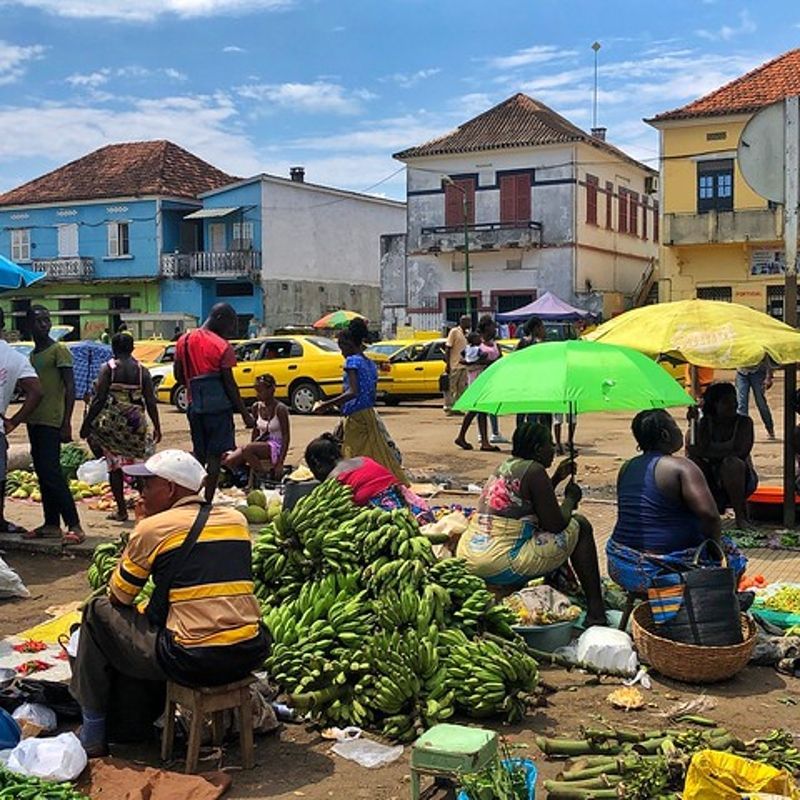 The bustling market in São Tomé City, São Tomé and Príncipe, is captured in this vibrant travel photograph, showcasing colorful stalls brimming with fresh fruits, vegetables, spices, and local goods. Vendors and shoppers engage in lively exchanges, highlighting the energy, culture, and daily life of the city. Bright fabrics, tropical produce, and handcrafted items create a rich tapestry of color and texture, reflecting the island’s traditions and heritage. The scene conveys the authenticity and vibrancy of urban life in São Tomé, offering an immersive glimpse into local culture, commerce, and community. Inspiration Africa specializes in bespoke, tailor-made journeys to São Tomé and Príncipe and across Africa, crafting unforgettable travel experiences in extraordinary destinations.