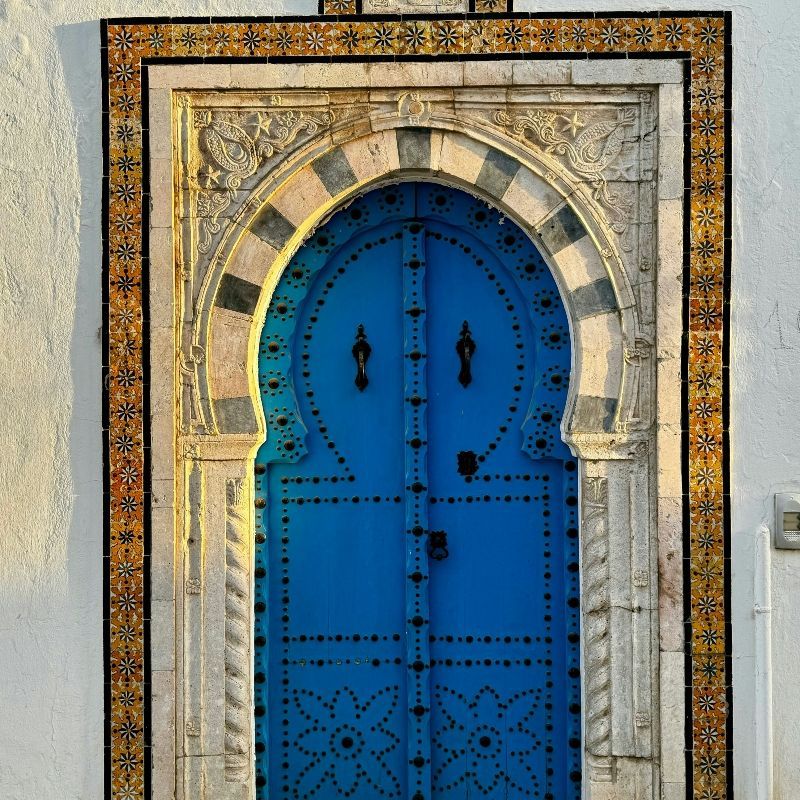 Experience the charm and vibrant culture of Tunisia with this captivating image of a traditional blue door. The photo captures the striking colour and intricate details of the door, set against whitewashed walls and adorned with subtle textures or surrounding flowers, reflecting the timeless aesthetic of Tunisian architecture. This scene evokes the beauty and serenity of the country’s medinas and coastal towns, showcasing the unique blend of history, culture, and artistry that defines Tunisia.
Inspiration Africa designs tailor-made journeys to Tunisia, offering travellers the opportunity to explore picturesque towns, discover traditional architecture, and immerse themselves in the colourful heritage and enchanting streetscapes of this North African gem.
