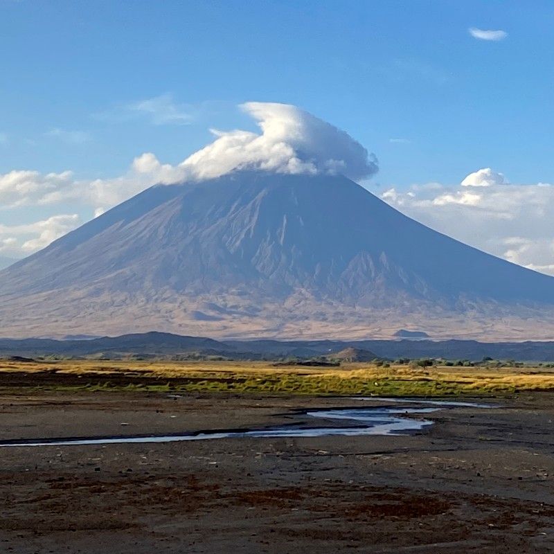 Ol Doinyo Lengai rising dramatically above the surrounding plains of northern Tanzania is captured in this striking travel photograph, highlighting the raw beauty and geological significance of one of East Africa’s most unique volcanoes. The steep volcanic slopes and rugged terrain create a powerful sense of scale and isolation, while soft natural light emphasizes the mountain’s textures and dramatic contours. Sacred to the Maasai people and often referred to as the “Mountain of God,” Ol Doinyo Lengai conveys an atmosphere of mystery, adventure, and cultural importance. The surrounding landscapes of open savannah and distant Rift Valley scenery enhance the feeling of remoteness and exploration. Inspiration Africa curates bespoke, tailor-made journeys to Tanzania and across Africa, combining extraordinary landscapes with immersive cultural and adventure experiences.