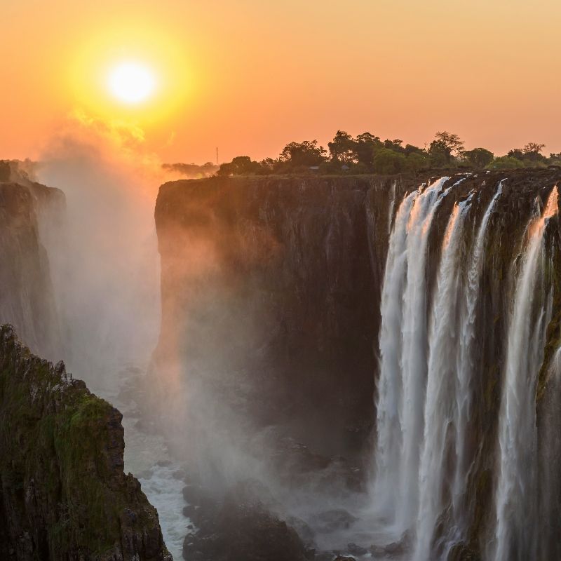 Witness the breathtaking grandeur of Victoria Falls from the Zimbabwean side at sunrise in this stunning photo. Golden morning light illuminates the cascading waters, creating misty rainbows that rise from the gorge and highlight the sheer power and beauty of one of the world’s most iconic waterfalls. The surrounding lush greenery adds depth and vibrancy to the scene, capturing the magic of this UNESCO World Heritage site. Inspiration Africa specializes in tailor-made journeys that immerse you in Africa’s most spectacular natural wonders. Let us design your personalized adventure to experience the awe-inspiring sights and sounds of Victoria Falls at the perfect moment of day.