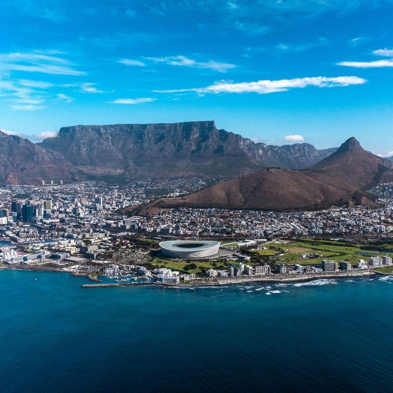 An aerial view captures the stunning cityscape of Cape Town, South Africa, with Table Mountain rising majestically in the background in this breathtaking travel photograph. The iconic flat-topped mountain towers over the city, framing colorful neighborhoods, harbors, and beaches, while the Atlantic Ocean stretches along the coastline. Cape Town is renowned for its dramatic scenery, vibrant culture, and diverse landscapes, blending urban life with natural beauty. Ideal for photographers, city explorers, and nature lovers, this scene highlights one of the world’s most picturesque cities from a unique vantage point. Inspiration Africa specializes in bespoke, tailor-made journeys to South Africa and across Africa, crafting authentic travel experiences that showcase extraordinary landscapes, iconic landmarks, and unforgettable destinations.