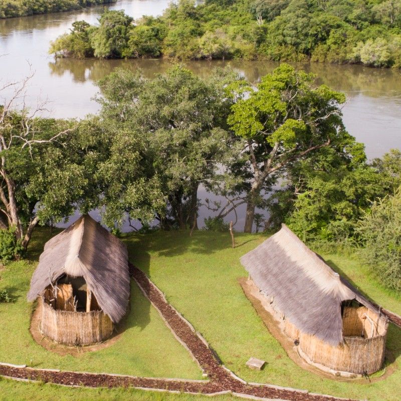 An aerial view of Mayukuyuku Bush Camp in Zambia is captured in this striking travel photograph, showing the camp nestled within the lush riverine and woodland landscapes of South Luangwa National Park. Canvas tents and natural structures are thoughtfully arranged to blend seamlessly with the surrounding vegetation, while elevated walkways and open spaces connect guests to the wilderness. The perspective emphasizes the camp’s remote and immersive setting, highlighting the harmony between safari accommodations and the rich wildlife habitat, where elephants, hippos, and other species roam freely. This image conveys the essence of an authentic Zambian safari experience, combining seclusion, comfort, and close proximity to nature. Inspiration Africa specializes in bespoke, tailor-made journeys to Zambia and across Africa, crafting unforgettable safari experiences in extraordinary wilderness destinations.
