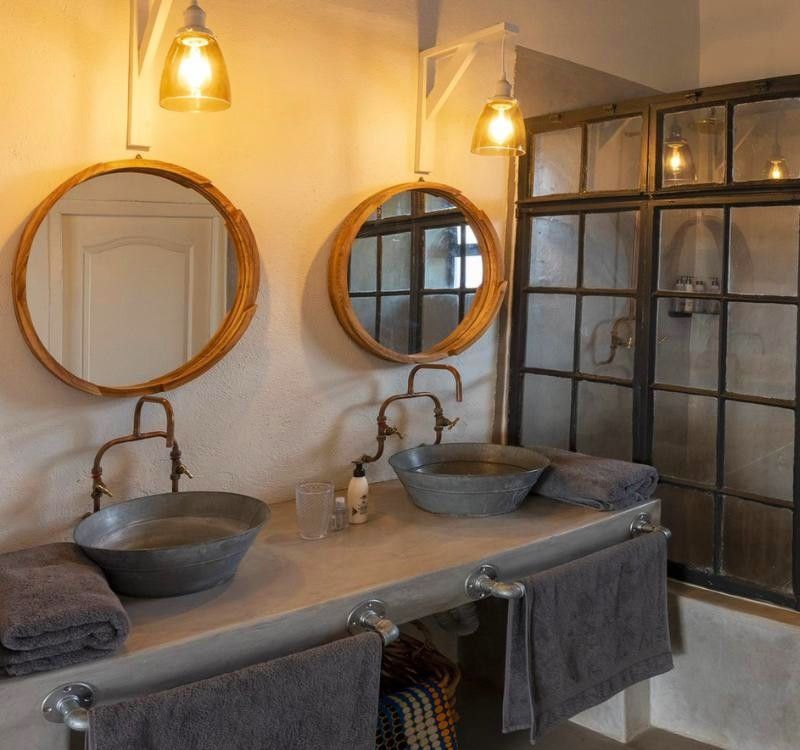 The bathroom in the superior room at Nantwich Lodge in Zimbabwe is featured in this refined travel photograph, showcasing a spacious and thoughtfully designed interior set within the remote wilderness of Hwange National Park. Clean lines, natural finishes, and quality fixtures create a sense of understated luxury, while soft lighting enhances the calm and relaxing atmosphere. Large openings or windows allow natural light to enter the space, subtly connecting the bathroom to the surrounding bush environment. The design balances comfort and functionality with a strong sense of place, offering guests a private and restorative space after a day on safari. This scene reflects the lodge’s attention to detail and commitment to providing comfort in a truly wild setting. Inspiration Africa specializes in bespoke, tailor-made journeys to Zimbabwe and across Africa, crafting unforgettable safari experiences in extraordinary wilderness destinations.