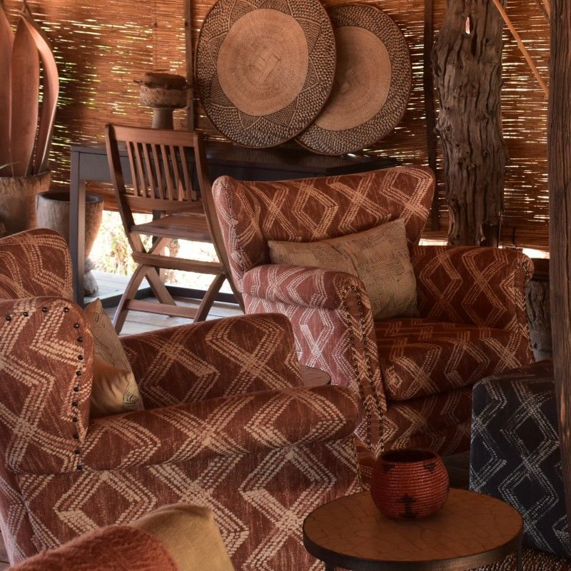 The interior of the communal area at Rhino Safari Lodge in Zimbabwe is captured in this welcoming travel photograph, showcasing a relaxed and thoughtfully designed space for guests to gather and unwind. Comfortable seating, natural wooden furnishings, and warm earthy tones create an inviting atmosphere that reflects the surrounding bush environment. Open sides and large windows allow natural light and fresh air to flow through the space, offering views of the lodge grounds and nearby wilderness. The communal area encourages conversation and relaxation between safari activities, embodying the spirit of shared experiences in the African bush. Inspiration Africa specializes in bespoke, tailor-made journeys to Zimbabwe and across Africa, crafting unforgettable safari experiences in extraordinary wilderness destinations.