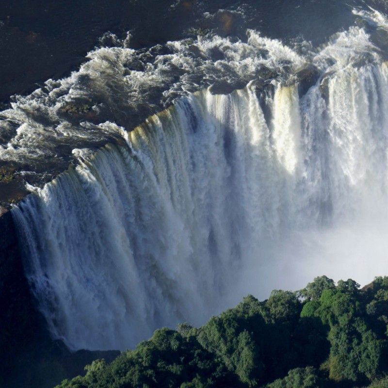A breathtaking aerial view reveals the immense power and sheer volume of water plunging into the gorge at Victoria Falls, one of Africa’s most awe-inspiring natural wonders. Seen from a helicopter flight, the scale, mist, and thunder of the Zambezi River create an unforgettable spectacle. Inspiration Africa specializes in bespoke, tailor-made journeys to Victoria Falls and across Africa, crafting extraordinary safari and adventure experiences in remarkable destinations.