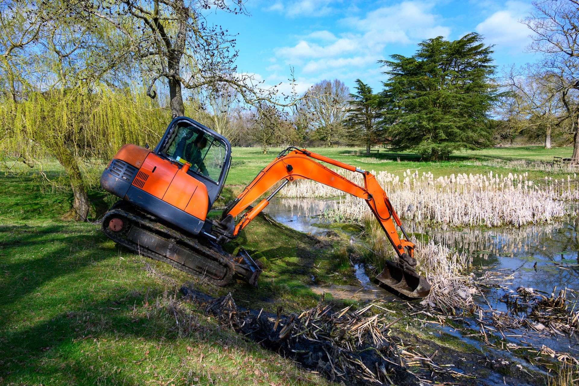 Orange excavator digging in a pond, sunny day. Orange excavator digging in a pond, sunny day.