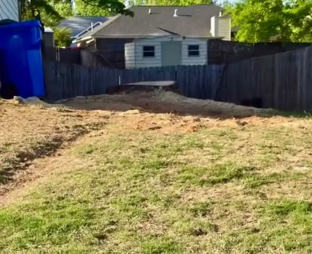 Backyard with patchy grass, a wooden fence, and a small gray shed near the back.