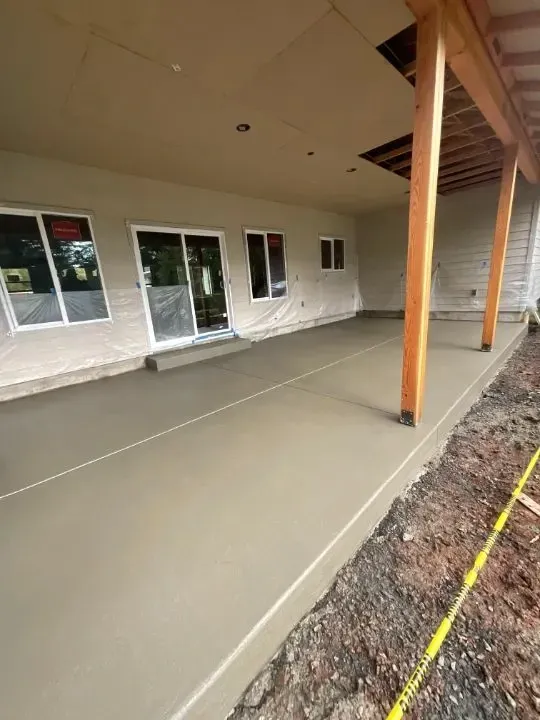 Concrete walkway beside house with black railing along a canal or water channel