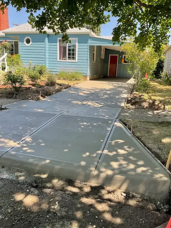 Concrete walkway beside house with black railing along a canal or water channel