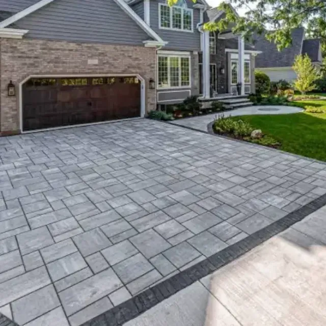 Paver driveway leads to a two-story house with a brown garage door.