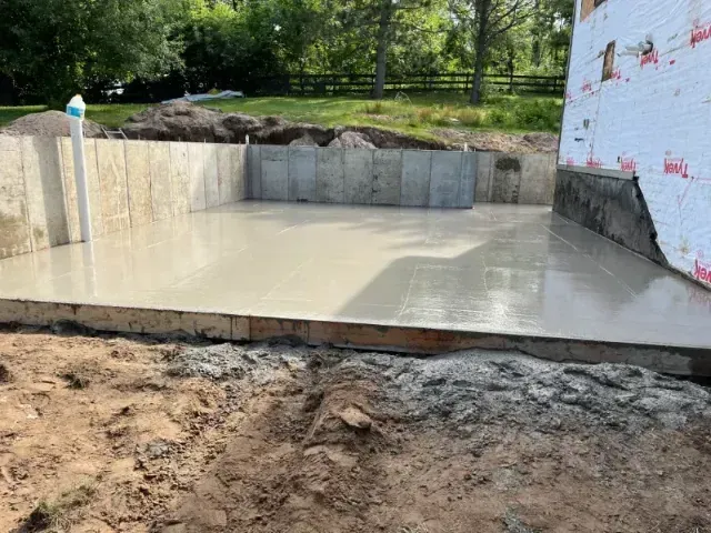 Concrete foundation with walls and a smooth floor, newly poured. Construction site, outdoor setting.