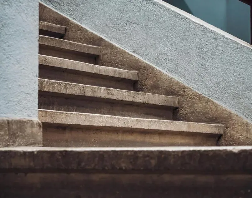 Concrete outdoor staircase ascending against a light blue wall.