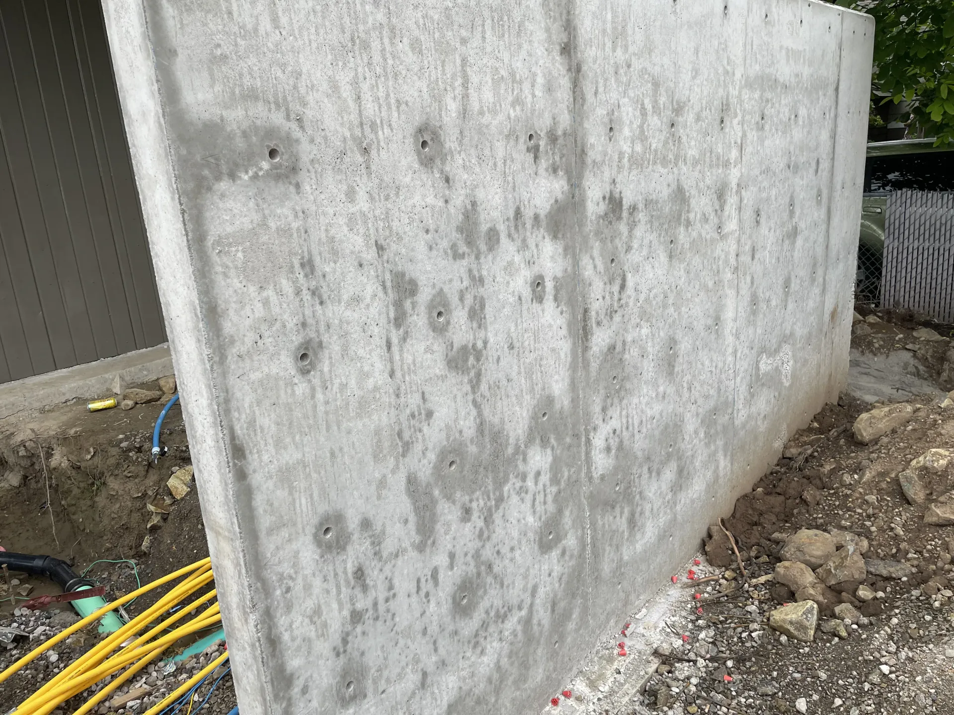 Concrete retaining wall beside dirt and yellow cables at a construction site