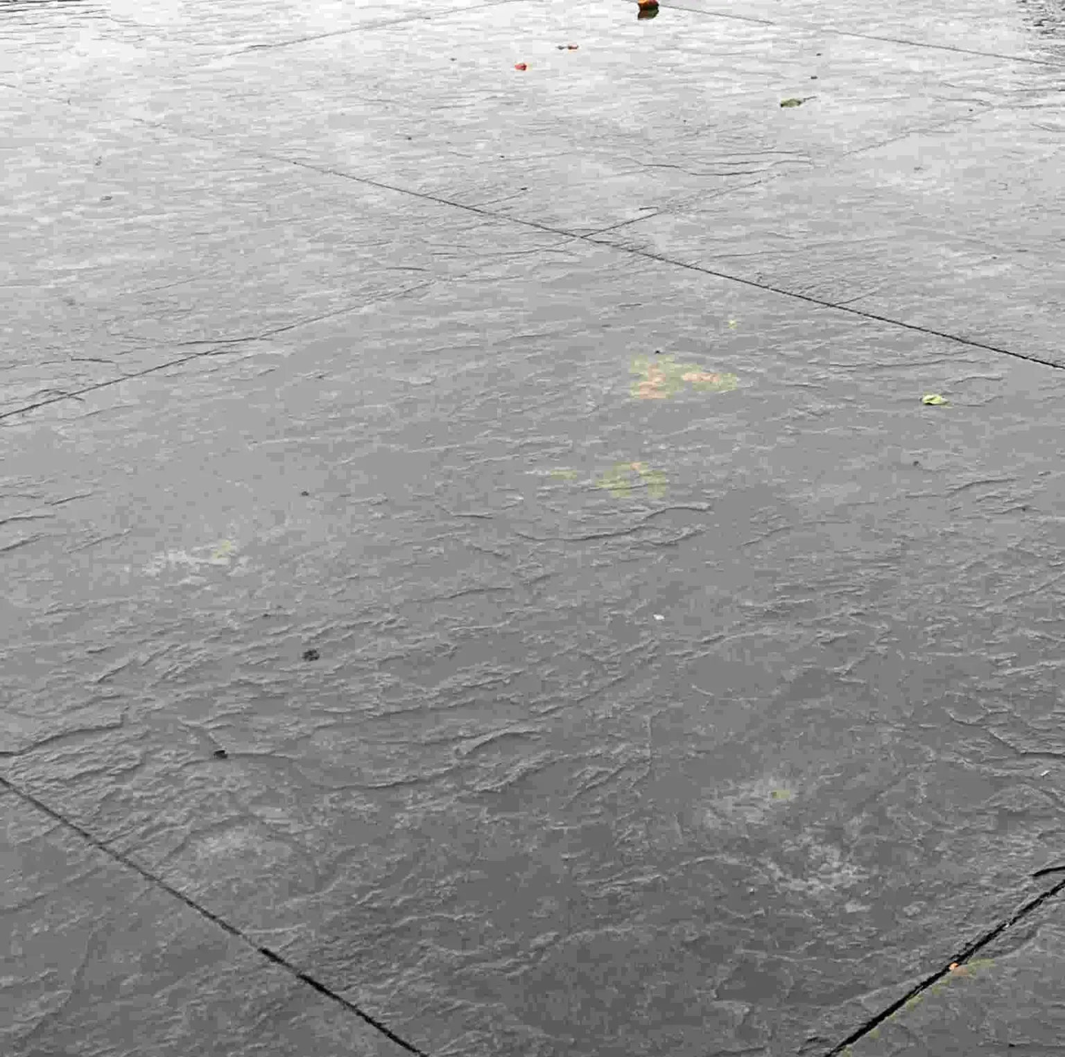 Close-up of grey, textured slate tiles arranged in a grid pattern with faint yellow surface markings.