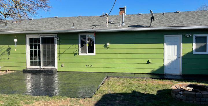 Concrete walkway beside house with black railing along a canal or water channel