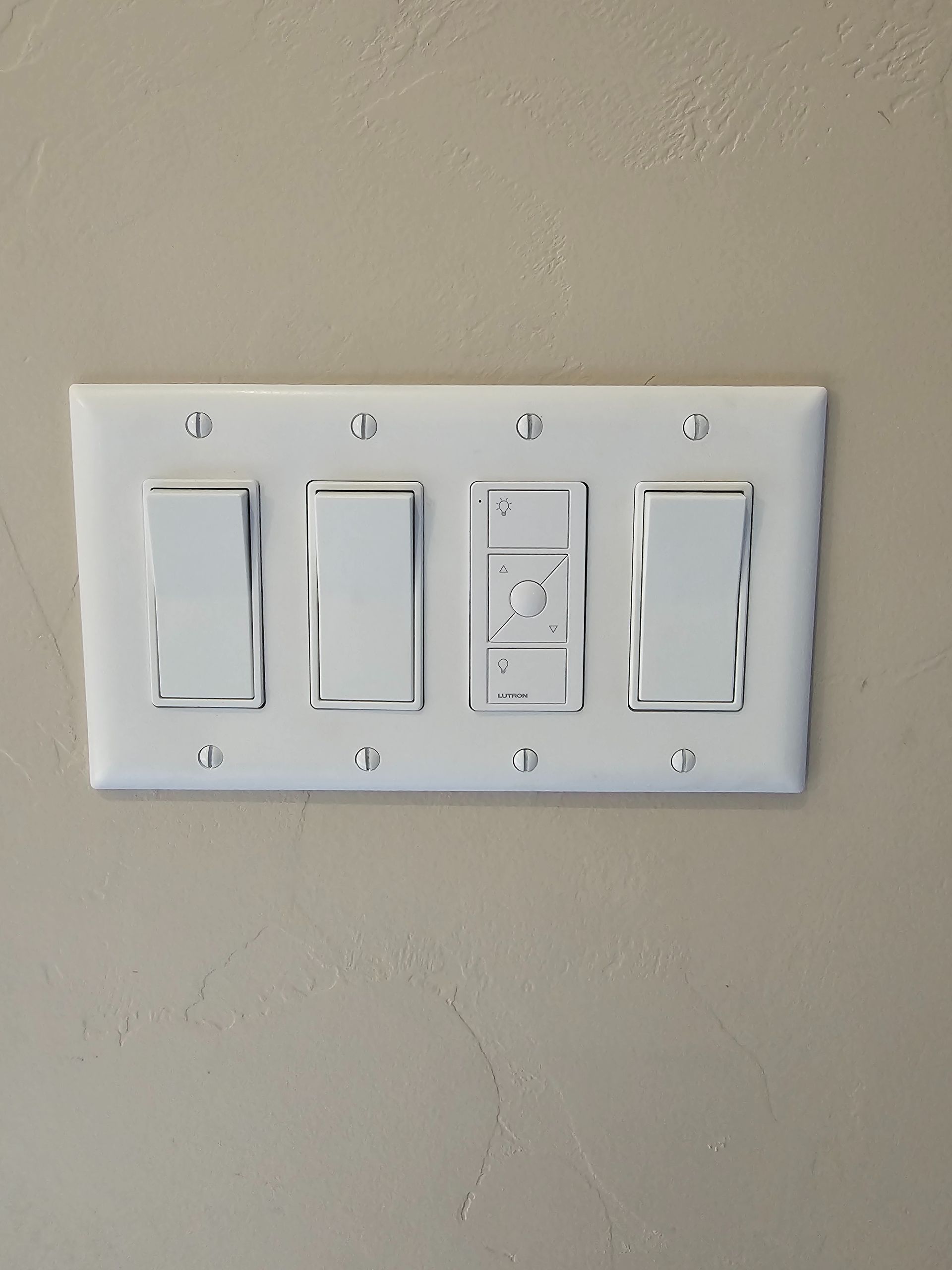 Four white wall switches and a dimmer panel on a beige wall