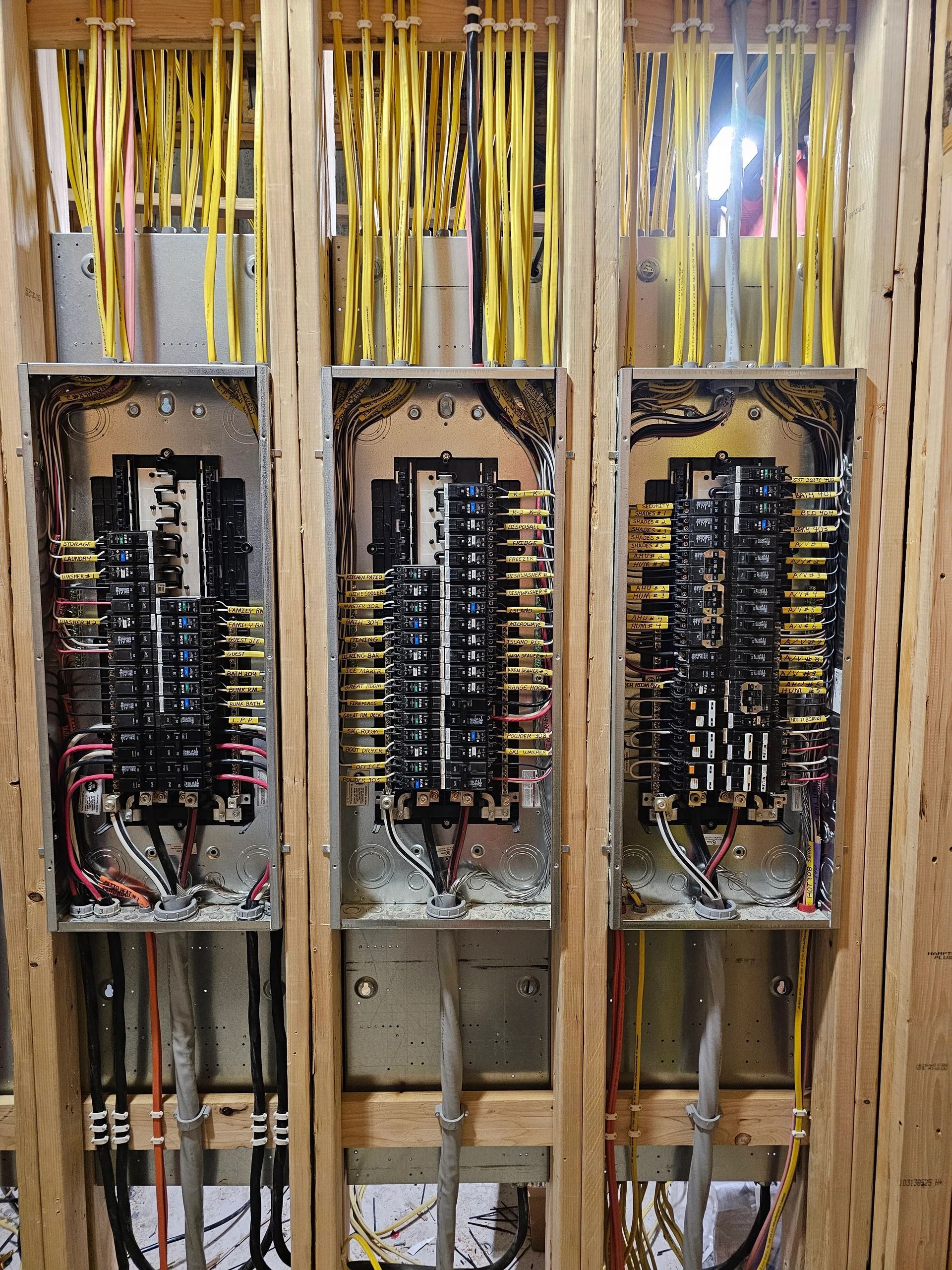 Open electrical panel with exposed wiring and breakers inside a wall cavity