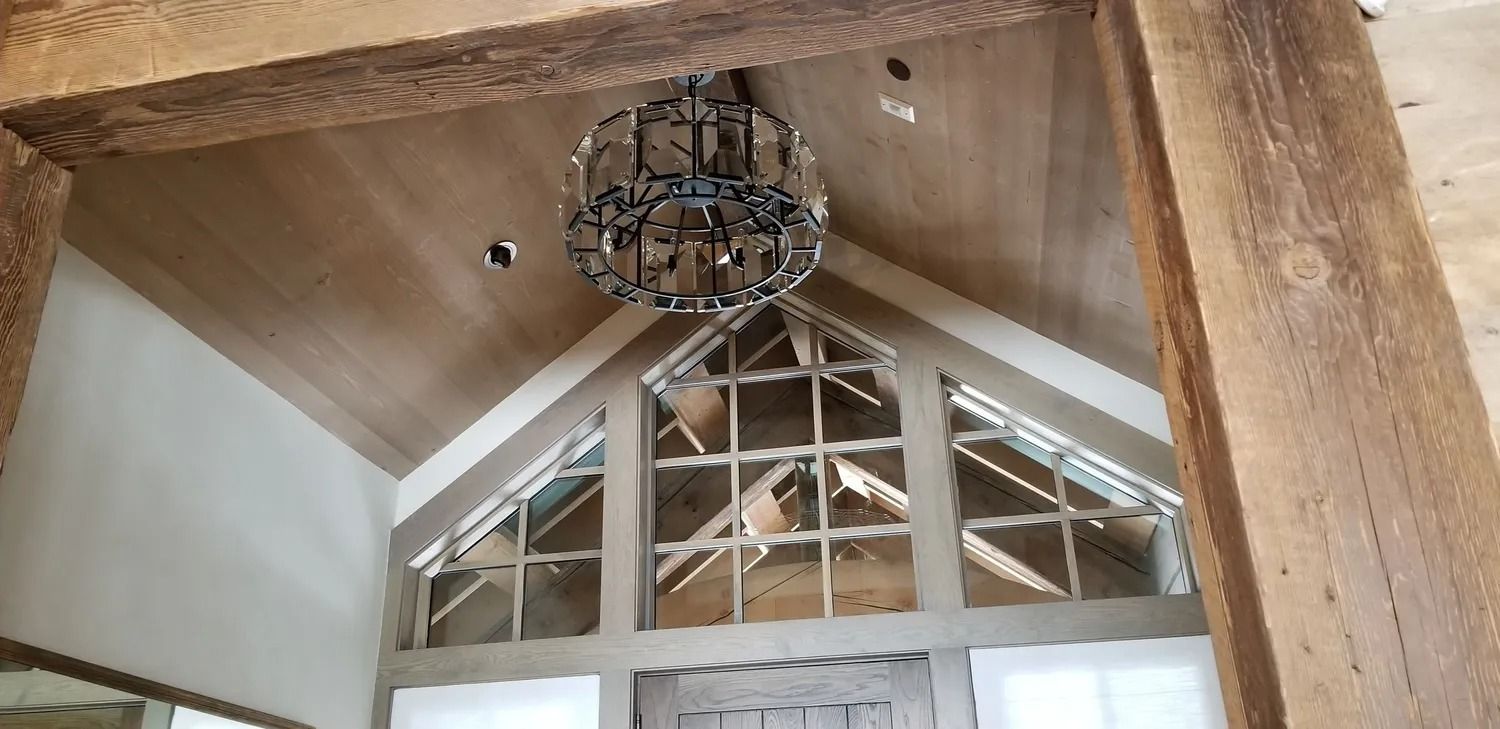 Wooden interior ceiling with a hanging wrought-iron light fixture above a peaked window