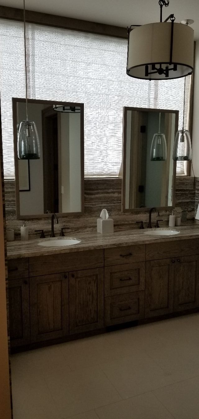 Bathroom vanity with double mirrors, wooden cabinets, and a hanging light fixture.