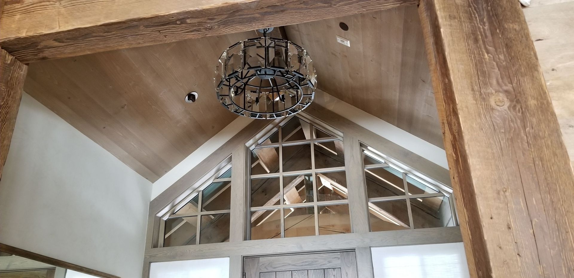 Interior view of a vaulted ceiling with a hanging chandelier and triangular window panes