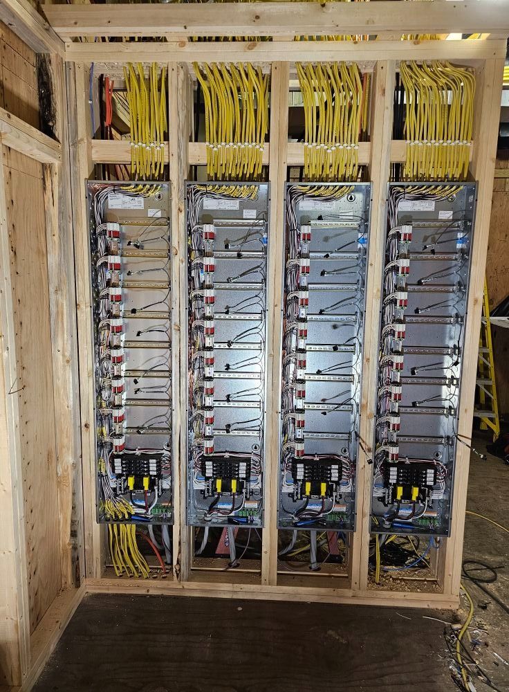 Rows of electrical control panels with yellow cables mounted in a wooden equipment room