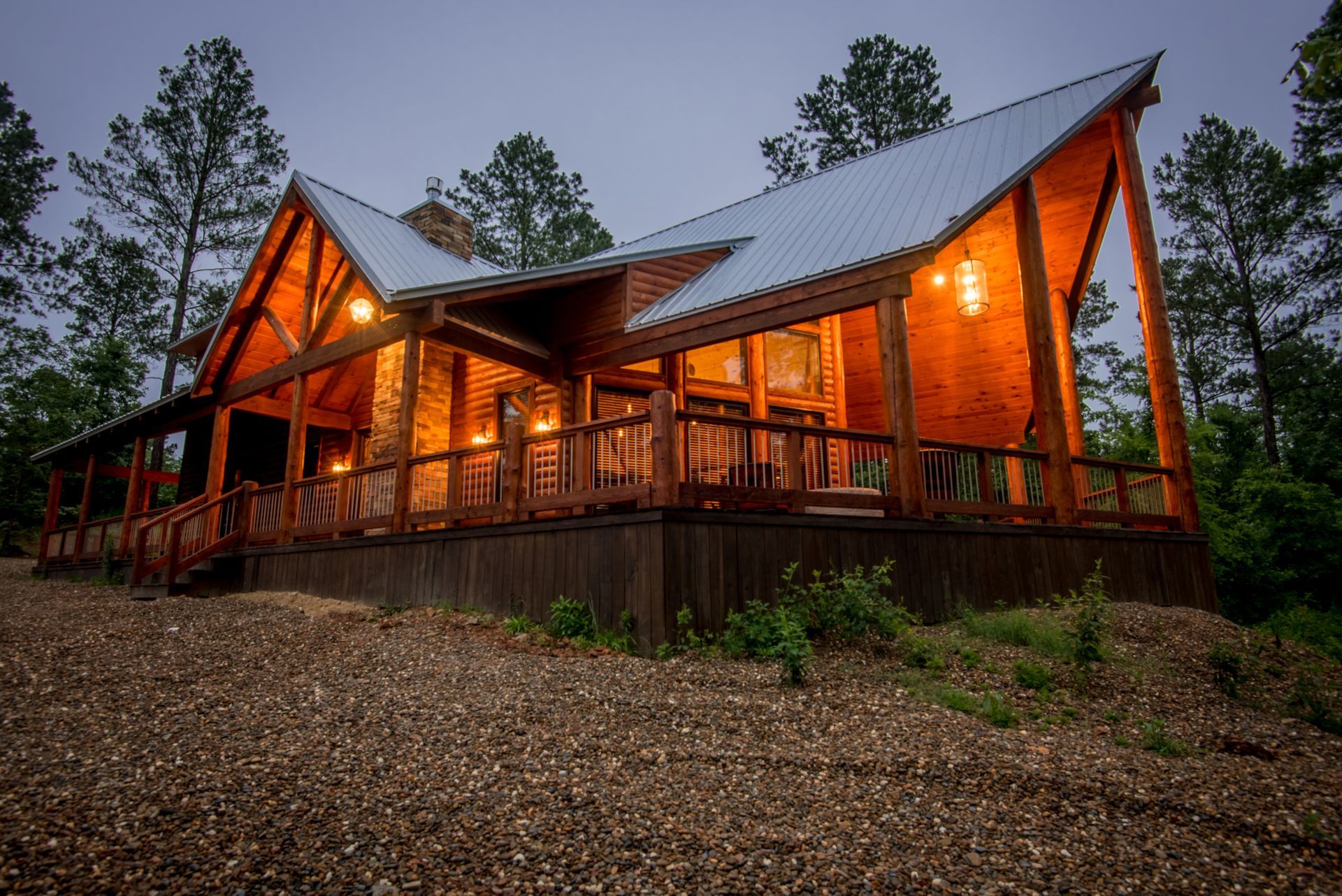 A large log cabin with a metal roof is lit up at night.