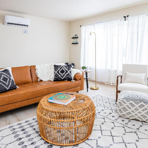 A living room with a couch , chair , coffee table and rug.