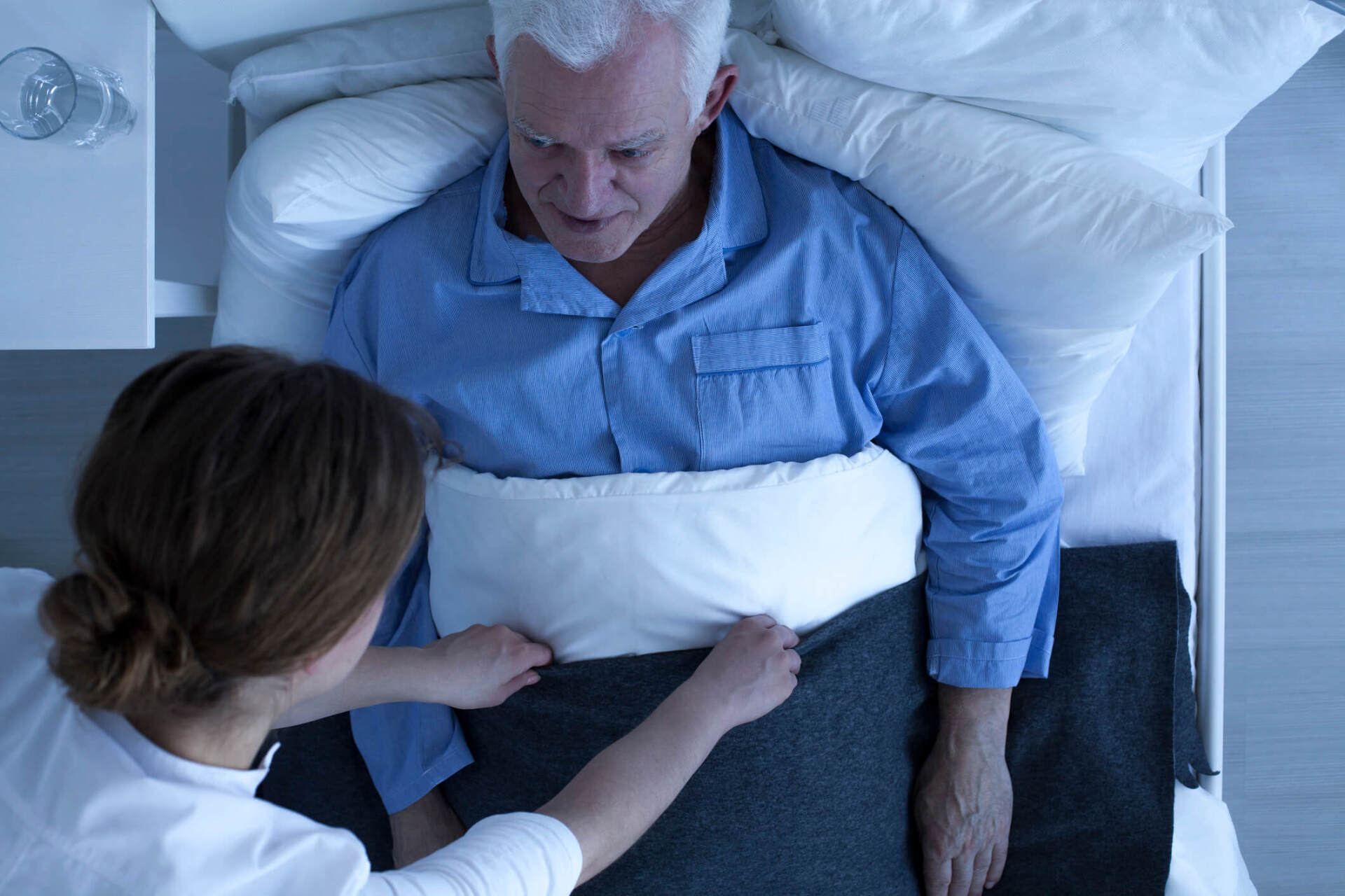 Anziano a letto che riceve servizio infermieristico notturno