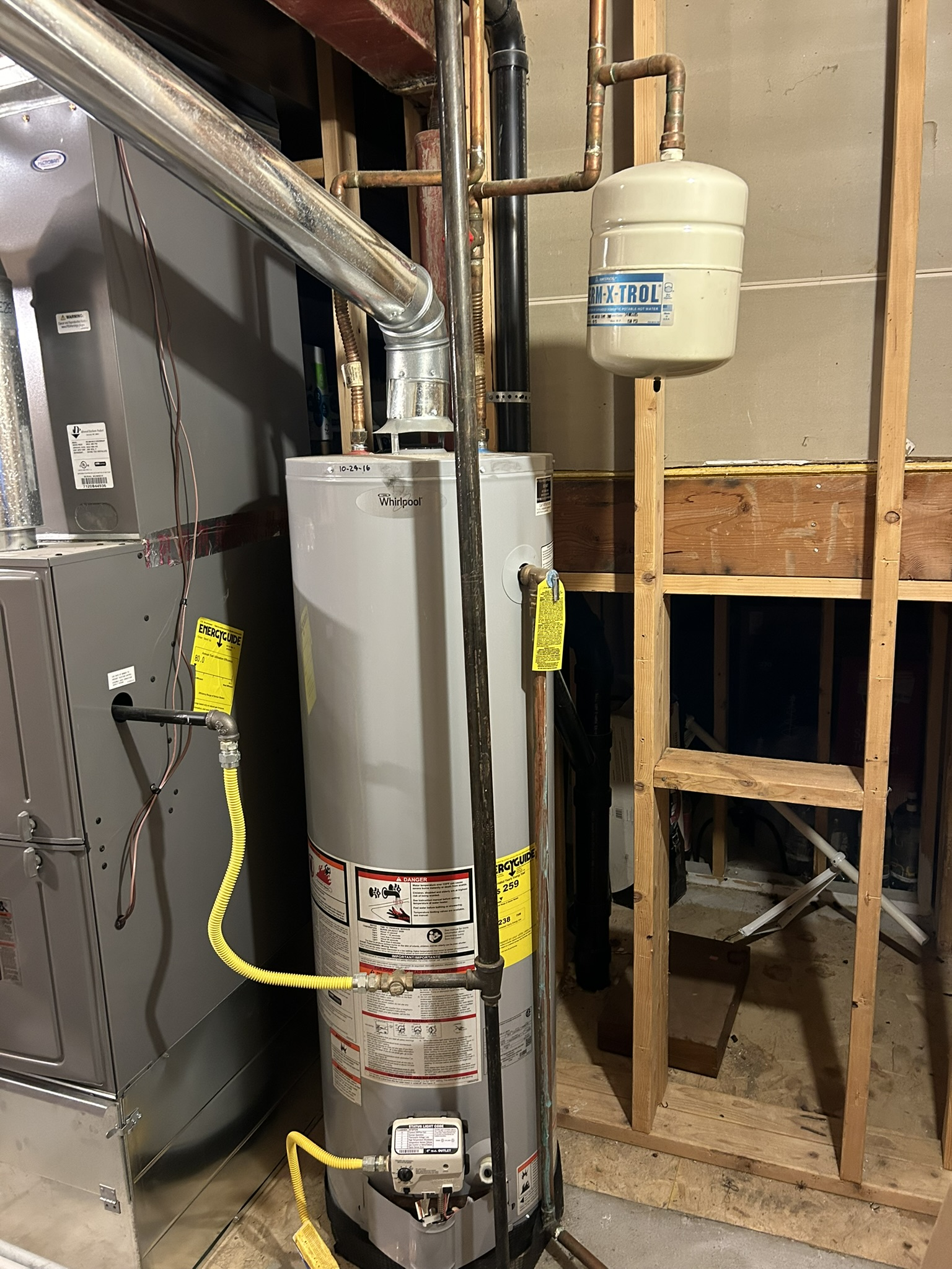 Water heater in a utility closet with exposed pipes, ductwork, and furnace equipment.