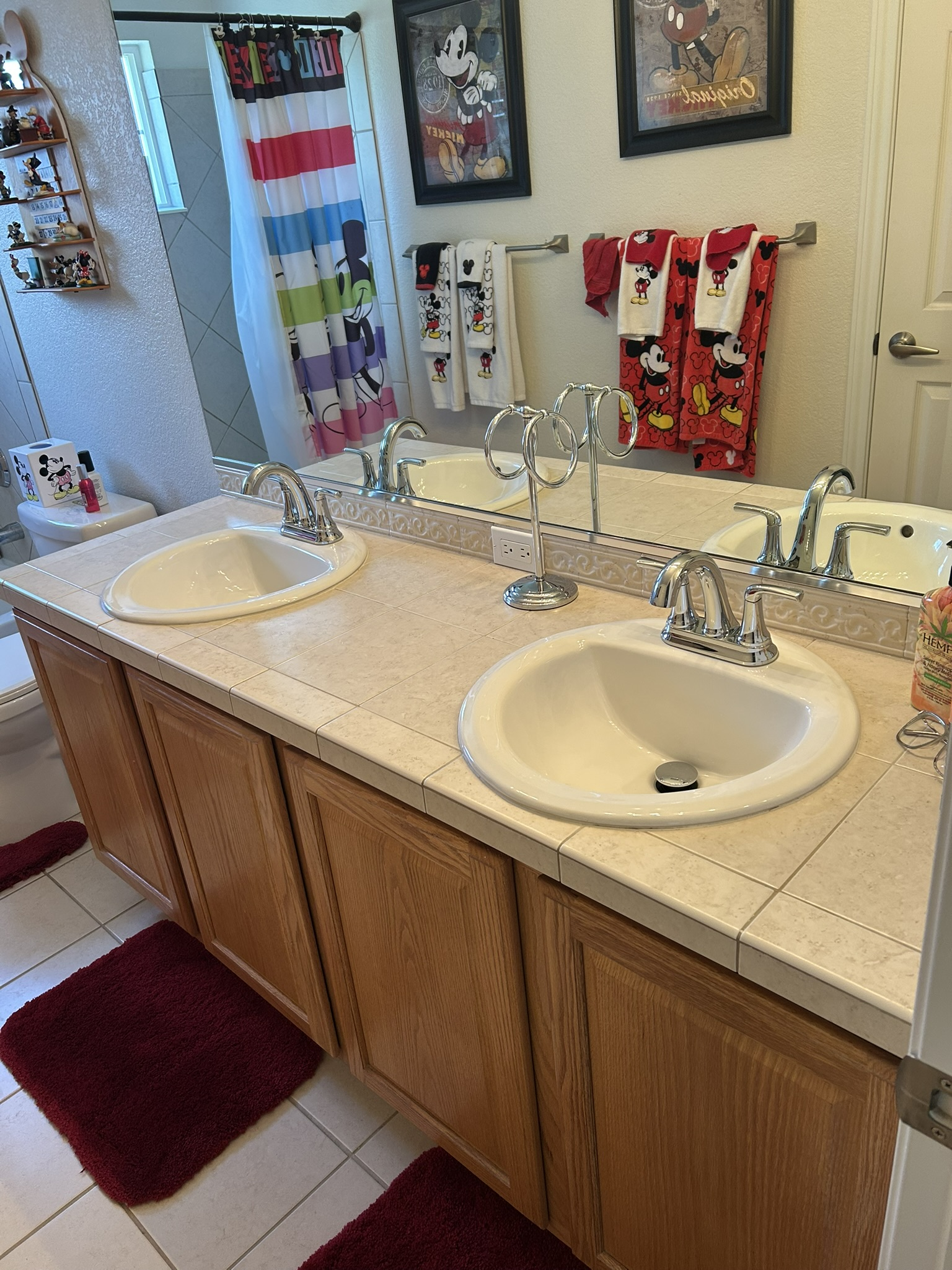 Bathroom vanity with two sinks, large mirror, and striped towels beside a shower curtain