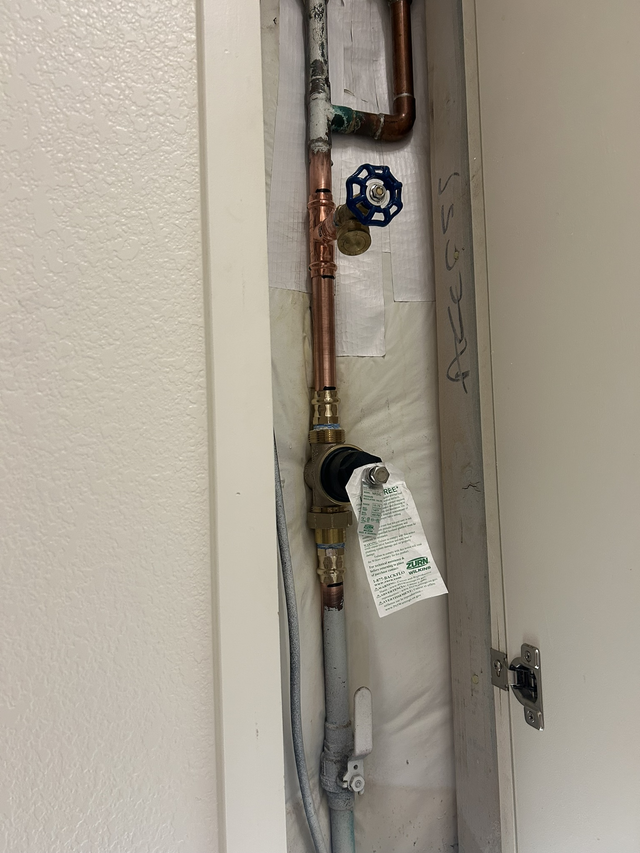 Water heater and furnace in a utility room with exposed framing and pipes.