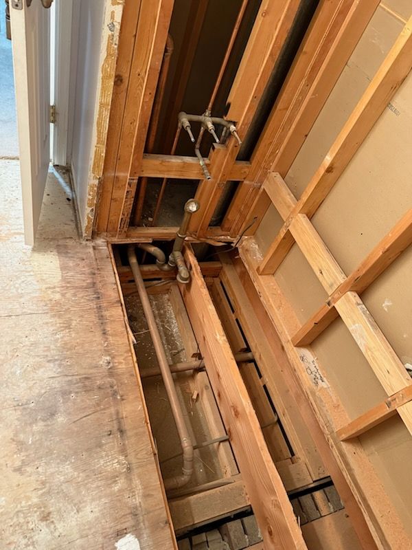 Exposed wall framing and wiring beside a doorway, with damaged drywall and open studs.