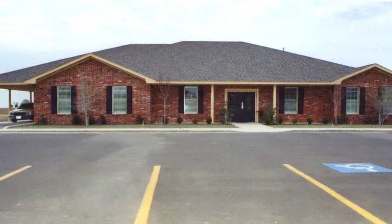 Peterson Funeral Home building with curved walkway, lawn, flowers, and sign at the entrance